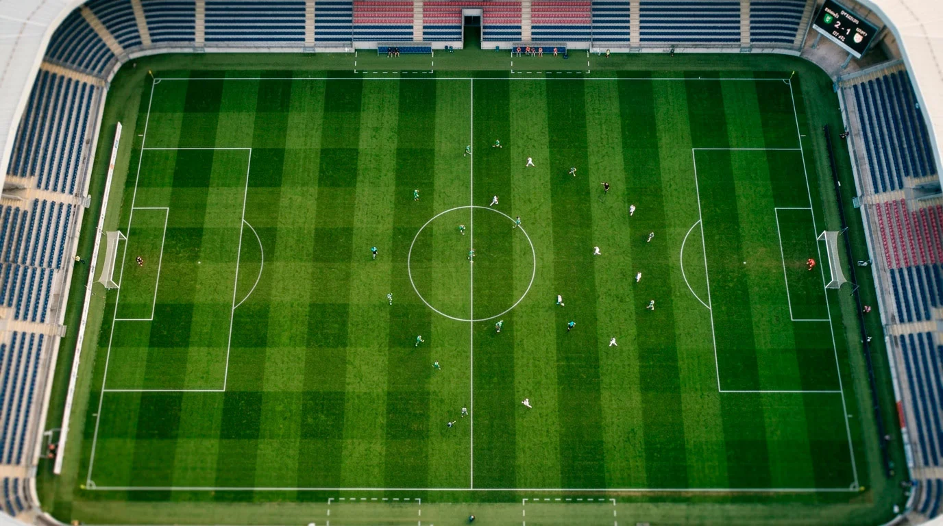 Zeleno nogometno igrišče z belimi črtami posneto iz ptičje perspektive pred veliko tekmo